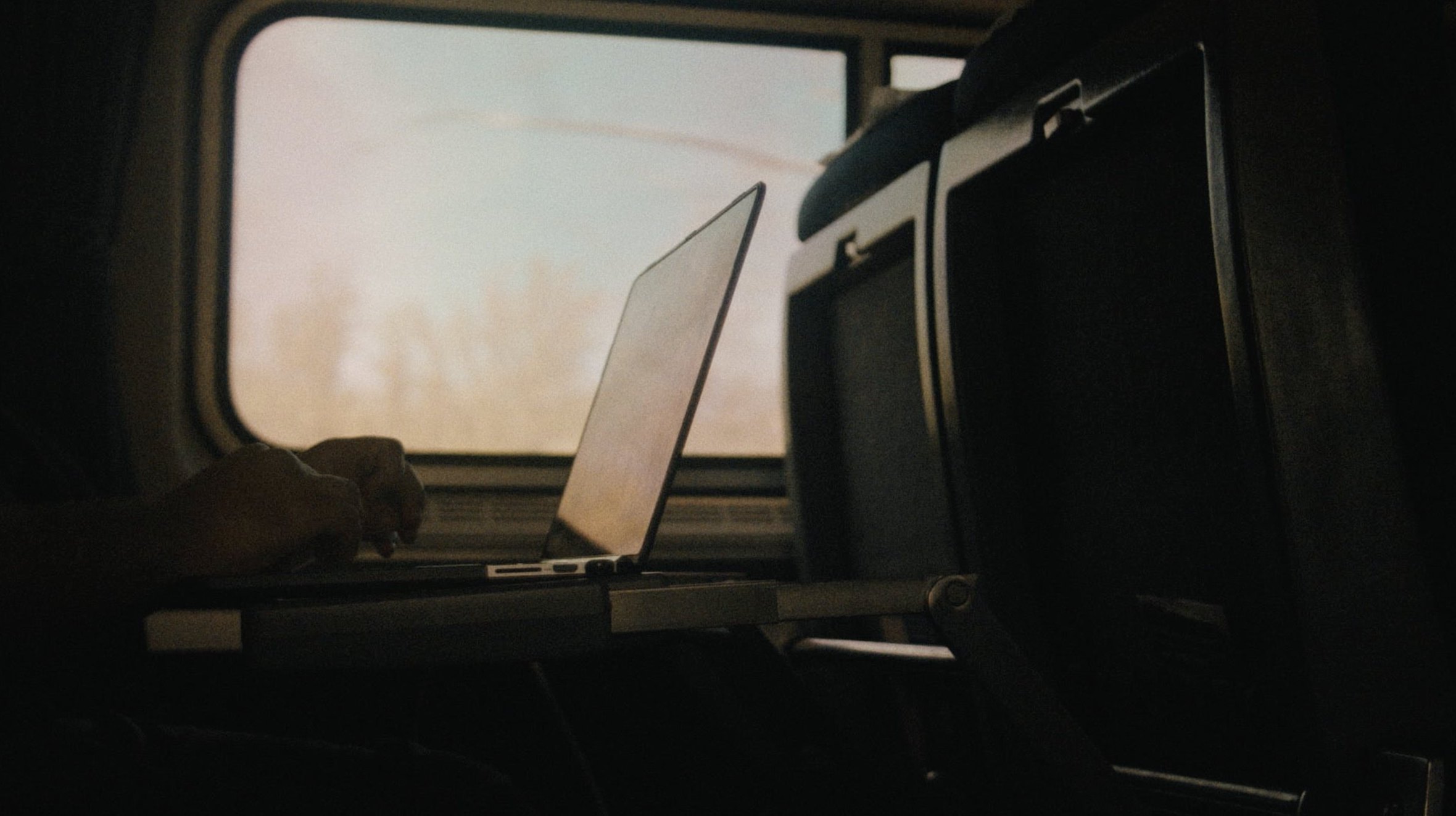 Silhouette typing on a laptop by a train window