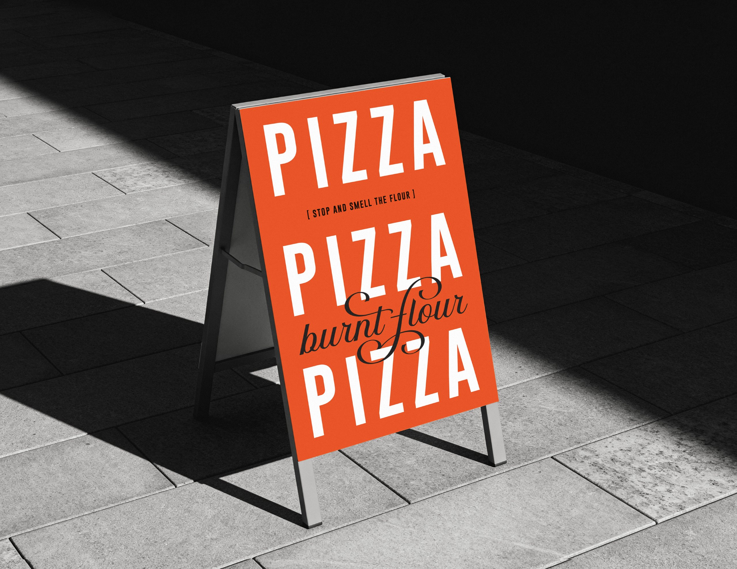 Orange Burnt Flour pizza sandwich board on a sunlit sidewalk