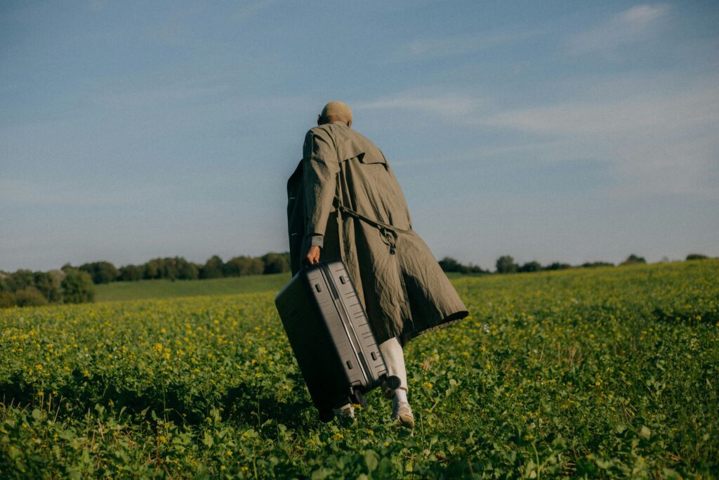 Traveller with a suitcase crossing a field, Hotel Railwayparc wordmark