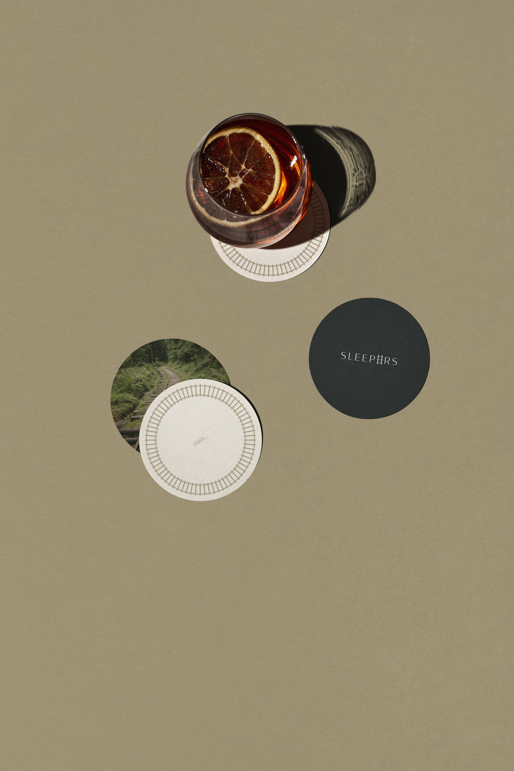 Sleepers coasters and a cocktail on a sage backdrop